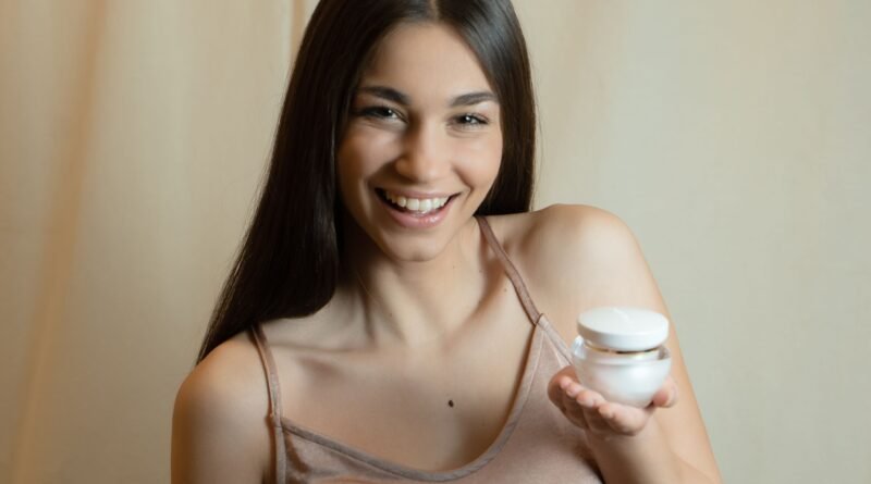 Smiling woman holding a small jar of face cream