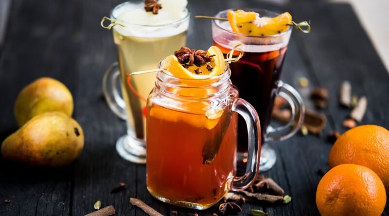 Warm spiced fall drinks with orange slices, pears and cinnamon sticks
