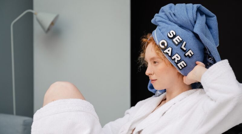 Woman in a bathrobe relaxing with a towel on her head that says self care