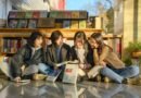 Four young women sitting outside a bookshop reading books together