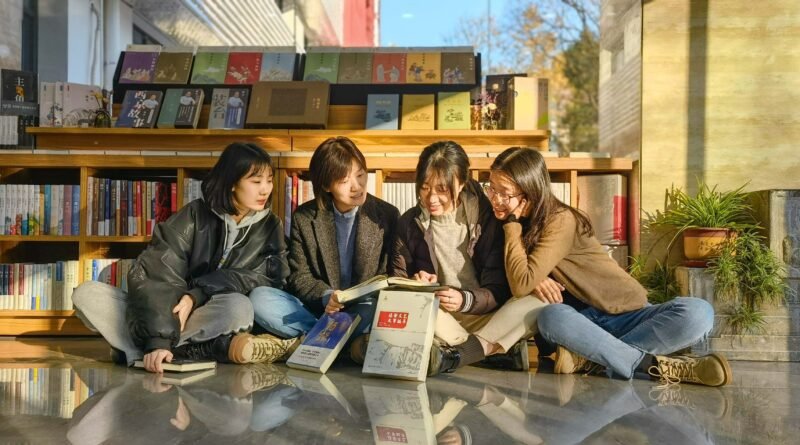 Four young women sitting outside a bookshop reading books together