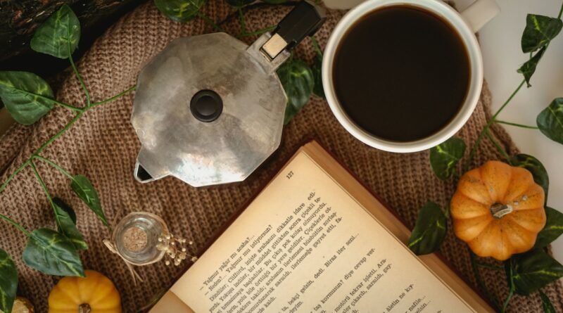 Cozy fall morning coffee with an open book, a moka pot and small pumpkins
