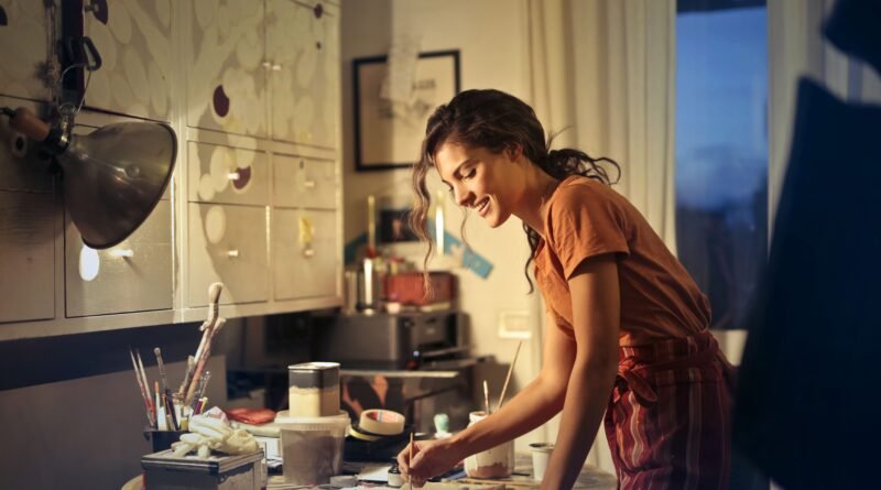 Smiling woman painting at a table at home in warm evening light